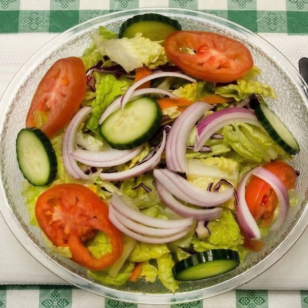 Fresh garden salad with lettuce, tomatoes, cucumbers, and red onions in a clear bowl.